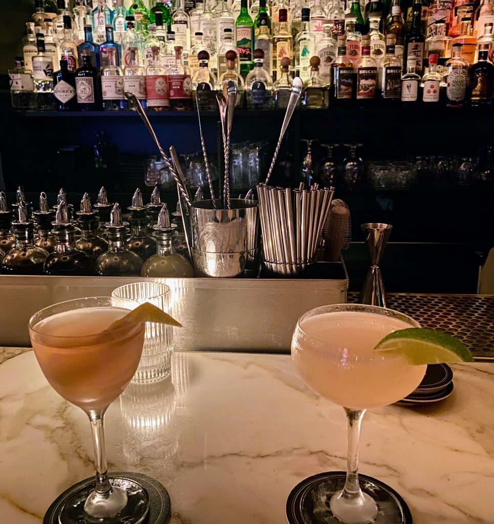 Two mixed drinks sitting on the marble bar at Death and Company