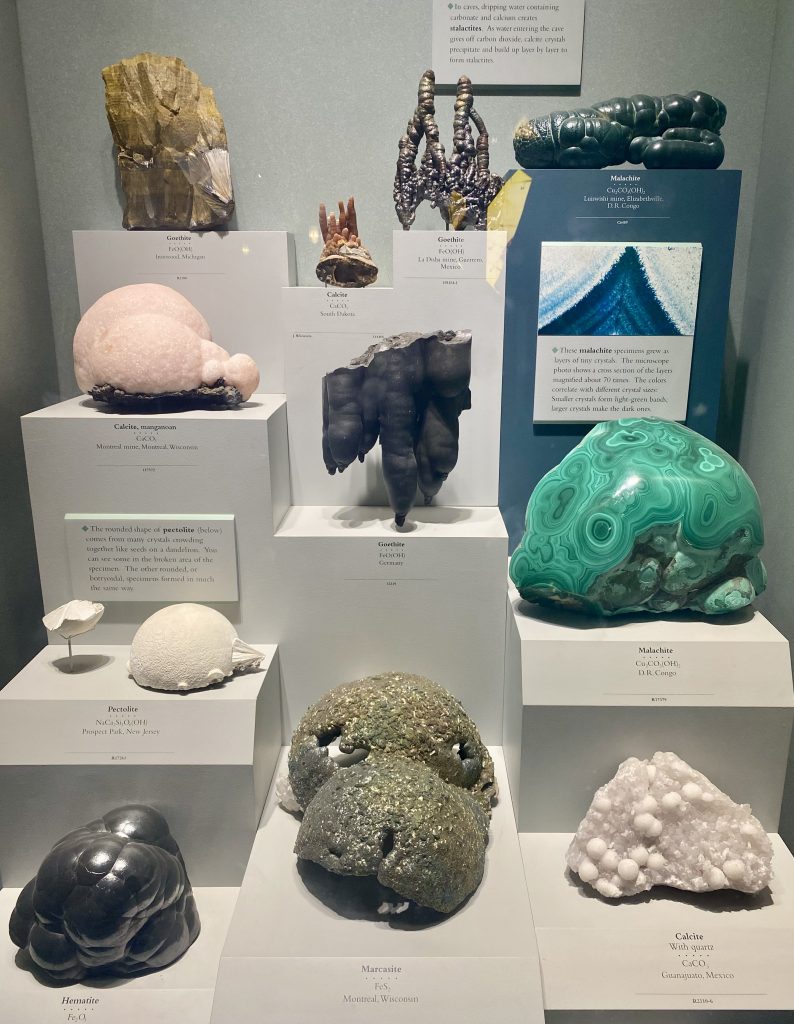 A display of rocks and minerals including hematite, marcasite, calcite, malachite, and pectolite