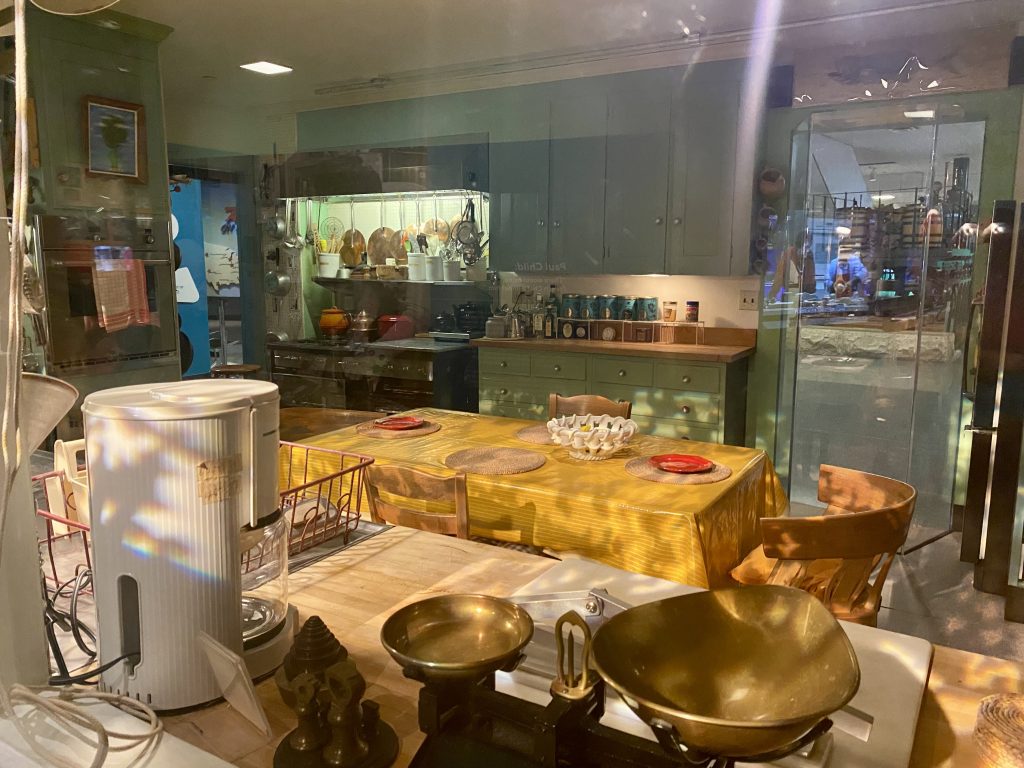 Model kitchen including coffee maker, dinner table with yellow tablecloth, chairs, green cabinets, oven, at National Museum of American History in Washington DC
