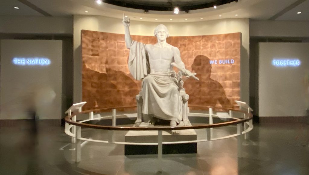Statue of seated man with his right arm raised at the National Museum of American History in Washington DC