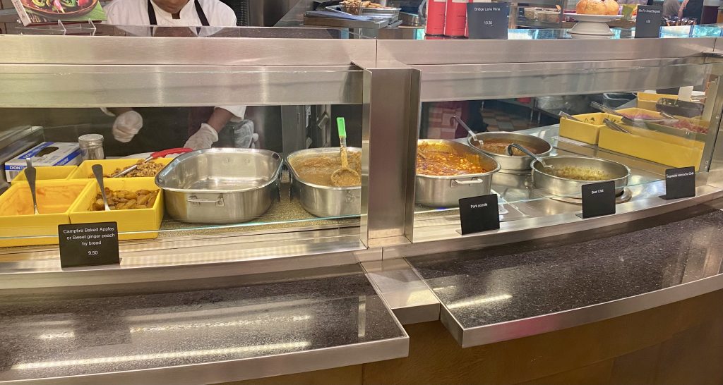 Dishes of food behind sneeze guard at cafeteria