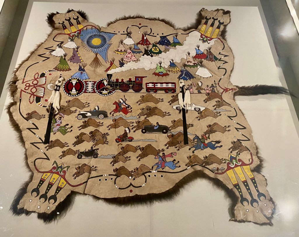animal hide colorfully decorated with buffalo, blue horses, black cars, a red train, and colorful tee-pees at the National Museum of the American Indian in Washington DC