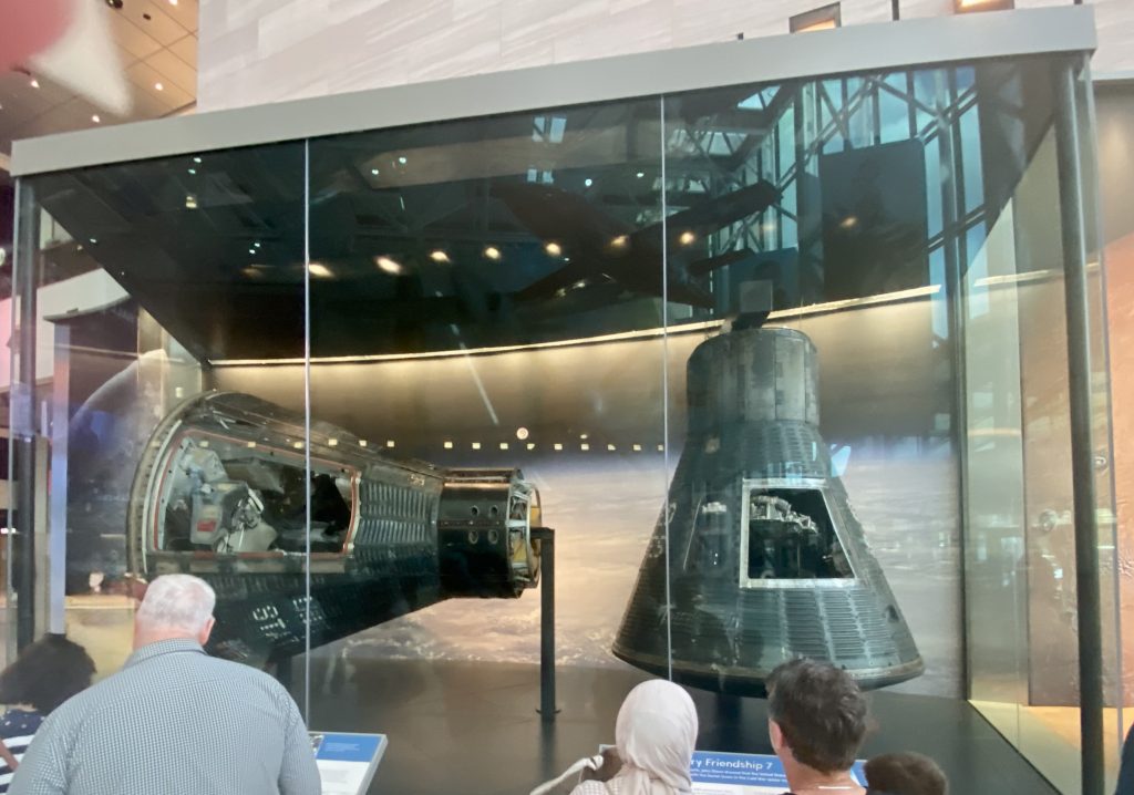 People looking at Mercury and Gemini space capsules in a glass display case at the National Air and Space Museum in Washington DC
