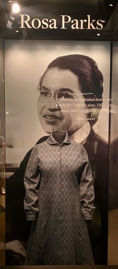 Display case featuring Rosa Parks' dress alongside a historical photo of her at African American History Museum in Washington DC