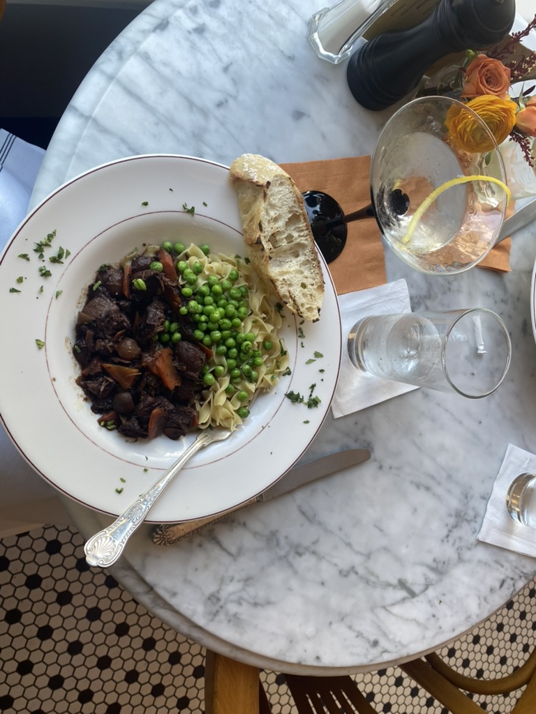 Plate with beef, peas, noodles, and bread on a marble table at Up on Market in Frederick Maryland