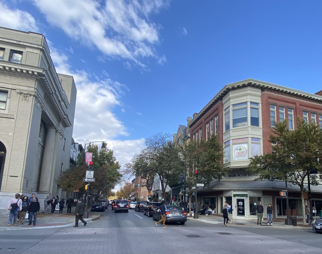 view down street in downtown Frederick Maryland with cars, people, trees, and stores