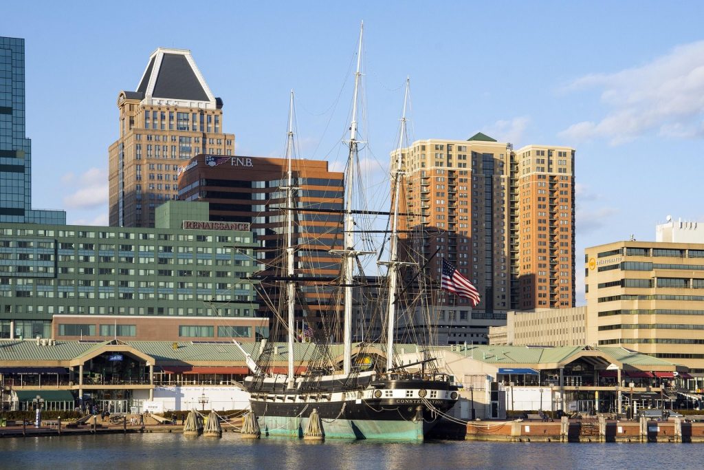Three mast ship in water in front of several tall buildings in Baltimore's Inner Harbor