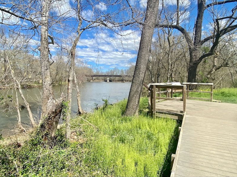 wooden pier overlooking Monocacy River with a bridge in the distance on Maryland hiking trail