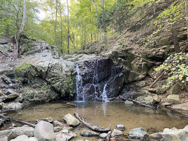 Small waterfall along jagged rocks spilling into small pool below along Maryland hiking trail
