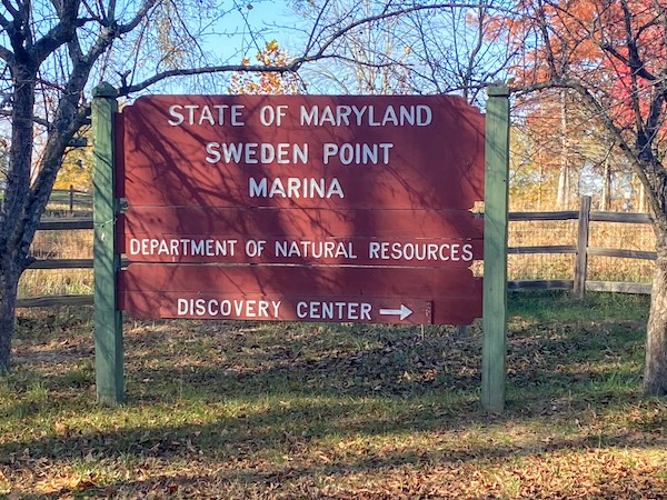 Red wooden sign that says "State of Maryland, Sweden Point Marina, Department of Natural Resources, Discovery Center"