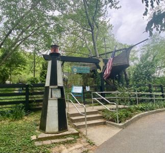 Small black and white lighthouse and American Flag at entrance to Glen Echo National Park Aquarium