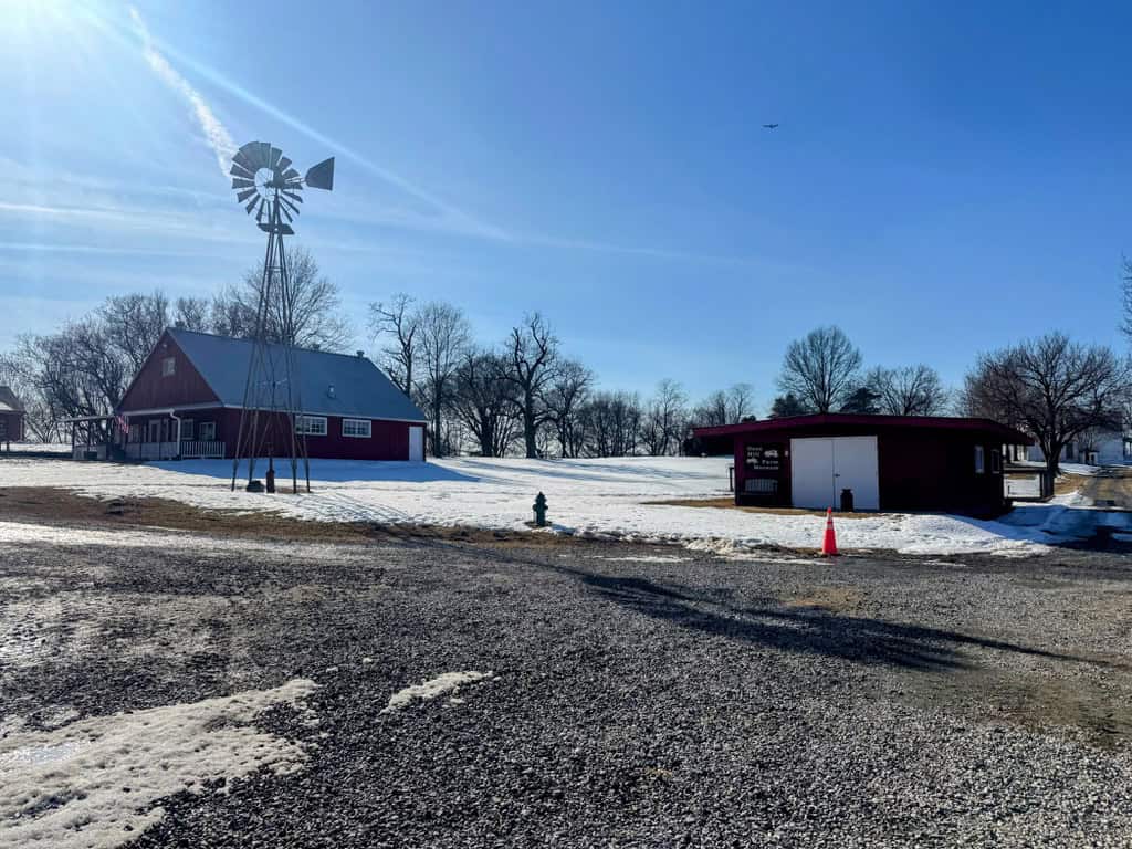 windmill on snowy hillside with red building in background
