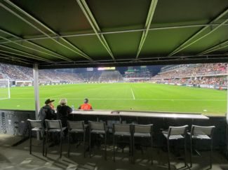 Looking out at green soccer field and stadium full of fans from ground level