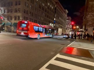 Red bus driving down city street in Washington DC at night